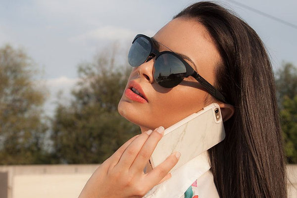 A woman wearing sunglasses and holding a white marble phone case