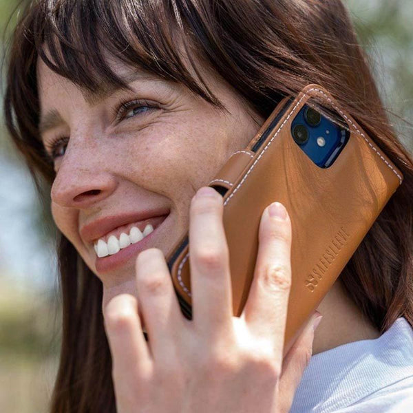 A woman smiling while talking on a phone in a wallet case