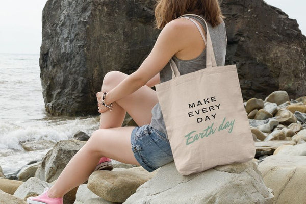 Woman by the ocean with earth day canvas tote bag