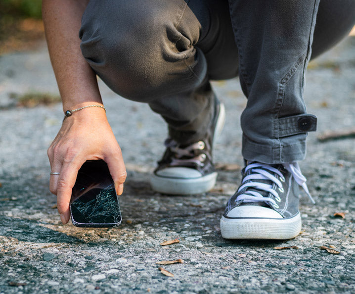 woman lifting cracked smartphone off the ground