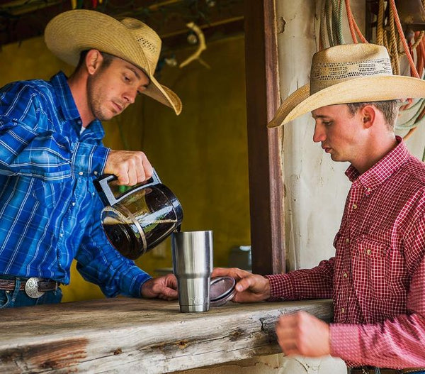 Two cowboys pouring coffee into yeti rambler tumbler