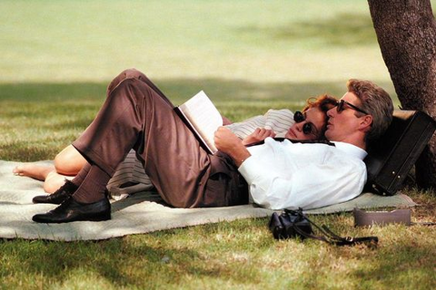 Couple laying down outside, reading