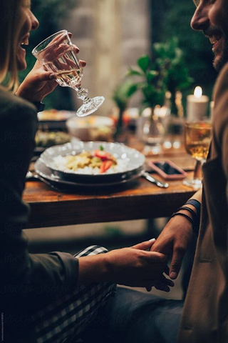 Couple, looking at each other, holding hands and having dinner