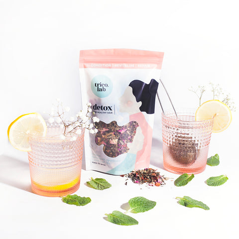 Trico.Lab Detox Organic Tea pouch with two glasses filled with tea and flowers around it