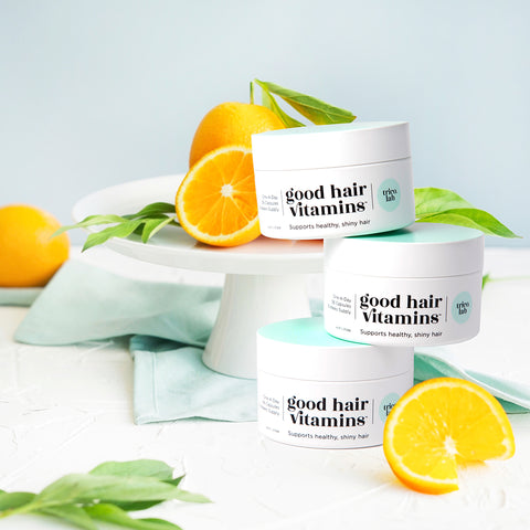 Trico.Lab Good Hair Vitamins stacked on top of each other with oranges and mint around it