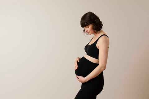 Pregnant woman wearing black leggings and bra