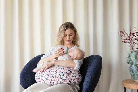 mother bottle feeding baby with nursing pillow