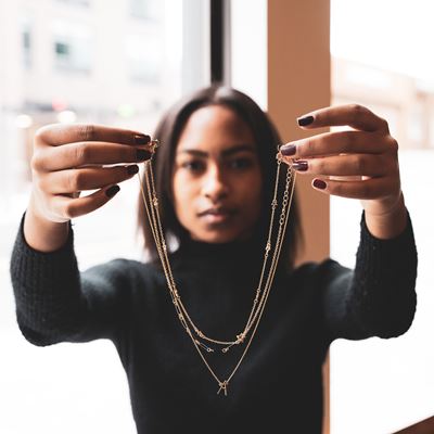 influencer holding necklet with three gold necklaces attached