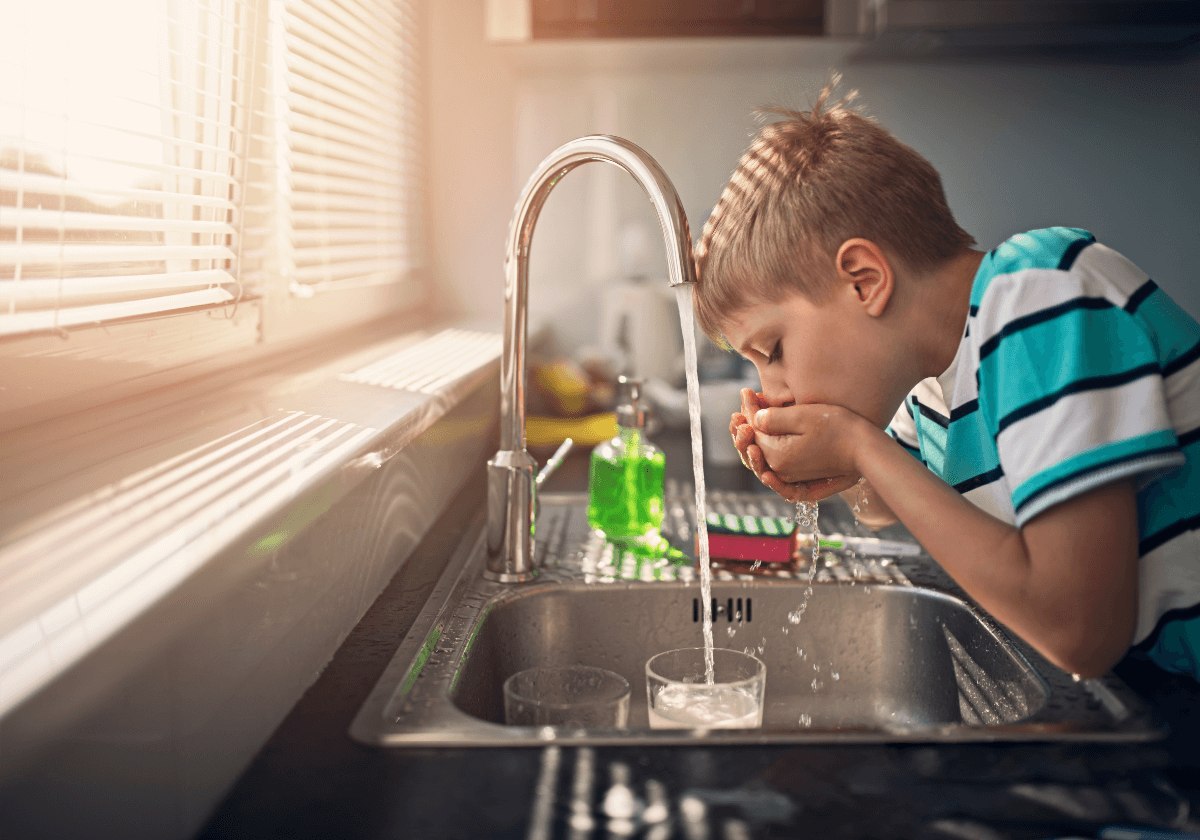 a boy drinking from the tap