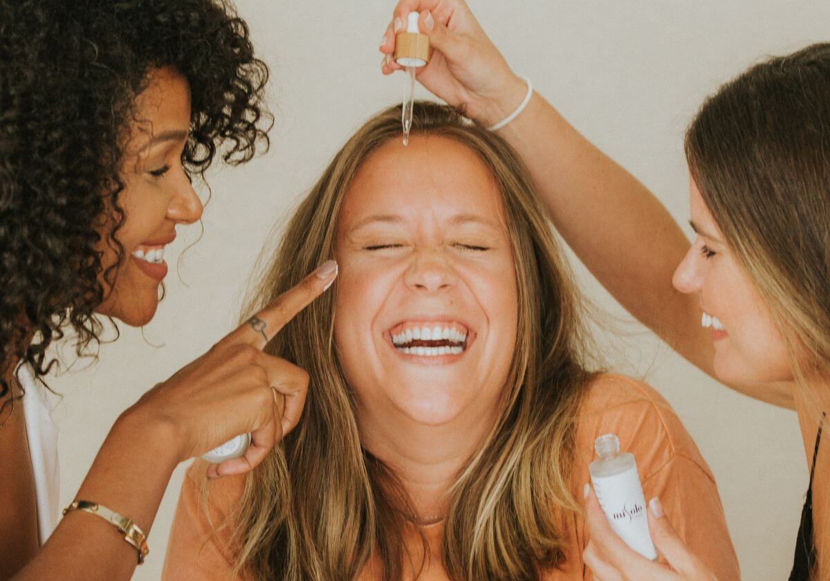 two girls helping their mom with skin care