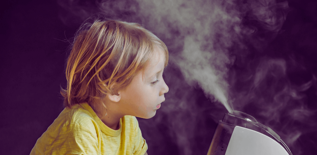 a child is next to a humidifier, gazing at the mist coming out of it