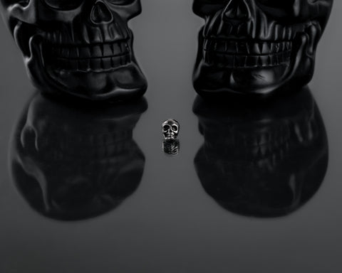 unisex skull earring on reflective black surface