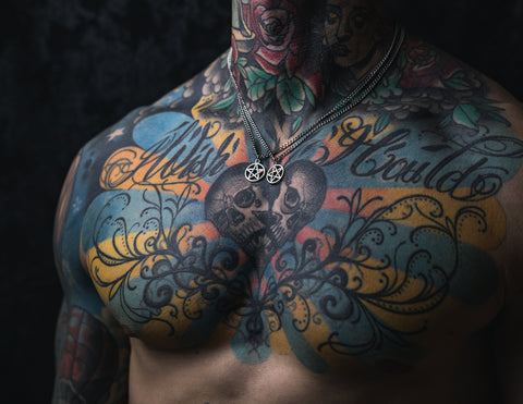 tattooed model with unisex pentagram punk necklace in dark shadow studio