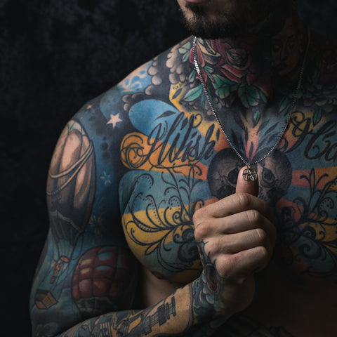 tattooed model with pentagram necklace in dark shadows