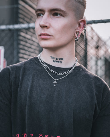Tattooed model wearing french cross on a punk rock necklace