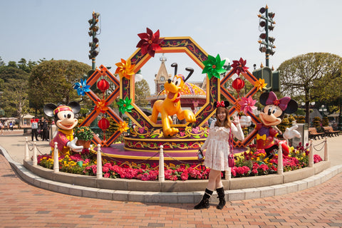 A young Disney fan poses with several classic Disney characters, including Pluto, Mickey, and Minnie. 