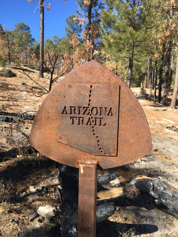 Rusted sign reads "Arizona Trail" with the shape of Arizona state showing the trail going across the state