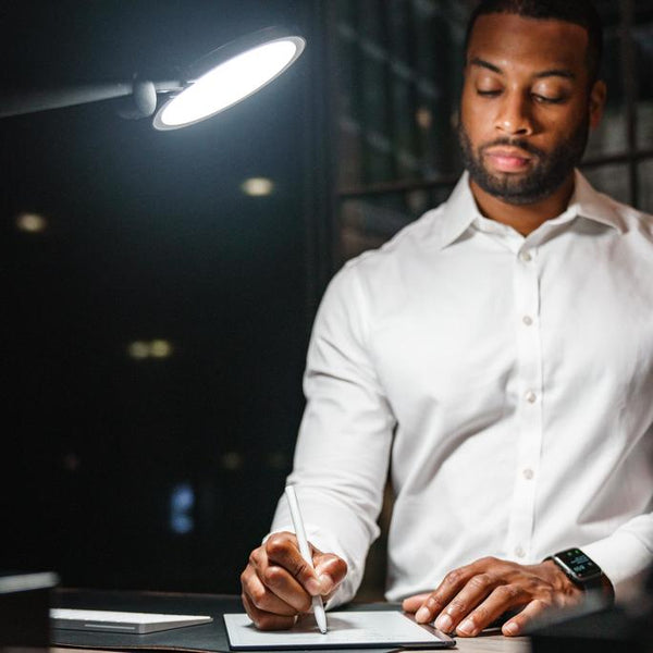 man using edge desk light writing notes