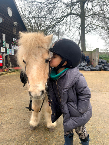 Child kissing a pony