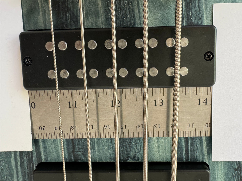 Photograph showing measuring a bass pickup with a ruler and two business cards