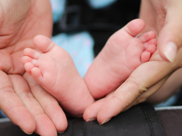 adult hands holding baby feet