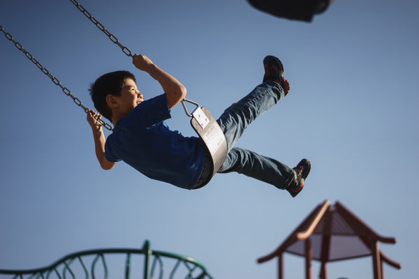 boy sitting on swing in playground