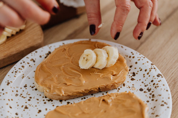 bread on plate with peanut butter and sliced bananas