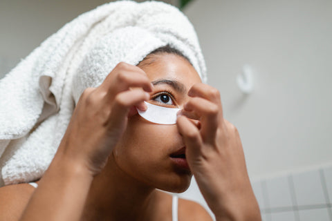girl with white towel on head applying under eye masks
