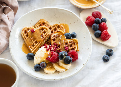 heart shaped waffles with fruit and honey on white plate