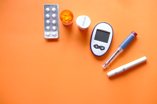 insulin pen diabetic measurement tools and pills on orange background