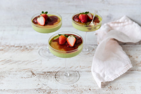 tall glass stemware filled with green panna cotta and strawberries