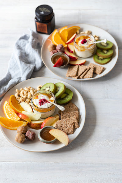 two snack plates with fruits nuts yogurt and honey