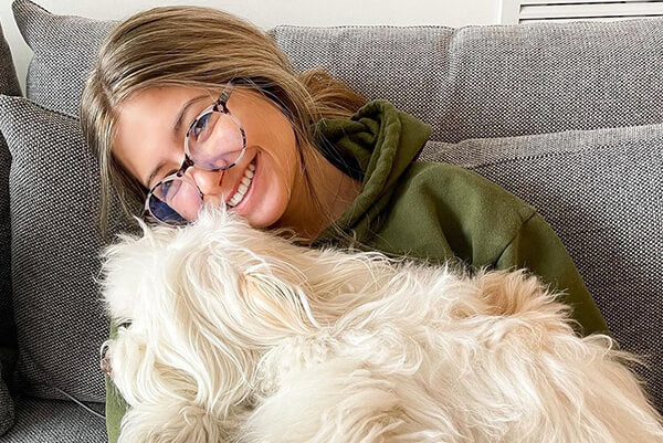 A girl hugging a dog wearing glasses