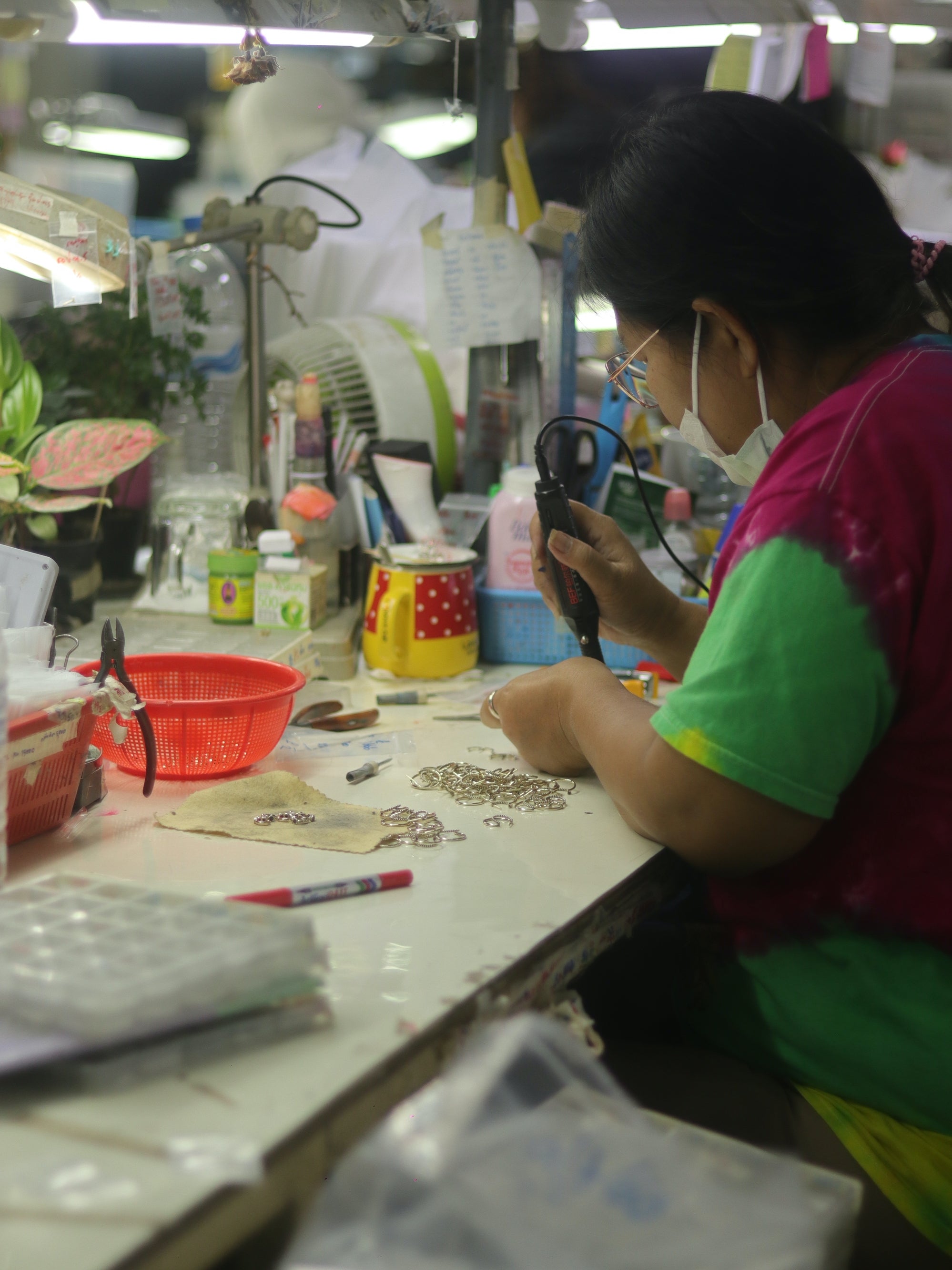 Woman in green working on jewelry at a desk