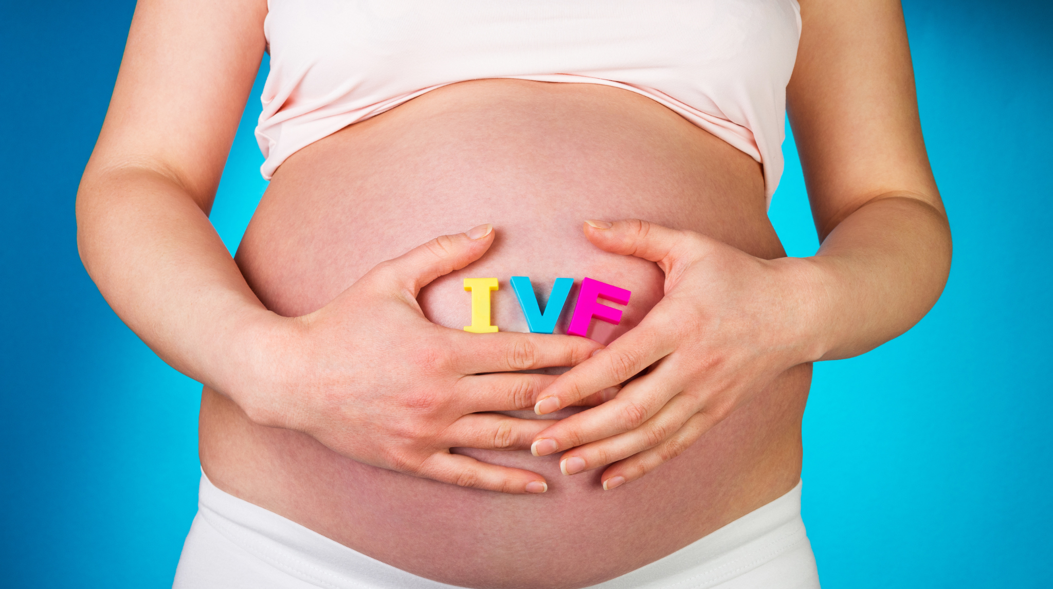 Pregnant woman holding IVF lettering | Neeva Baby