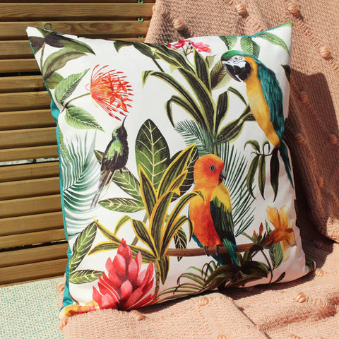 A cushion with a parrots and plants design