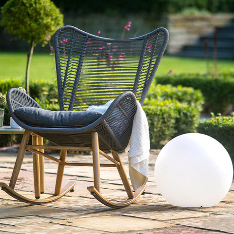 A white sphere light outdoors next to a grey rattan rocking chair