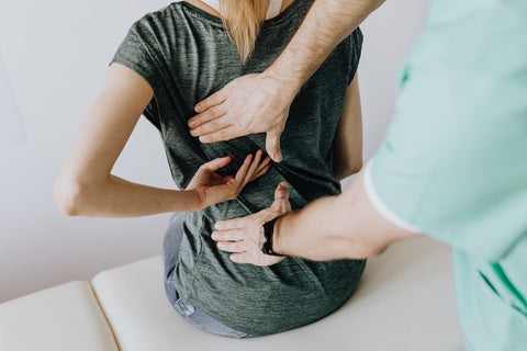 Woman at chiropractor's office because sitting on office chair without lumbar support