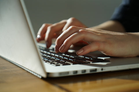 man typing at desk on apple laptop