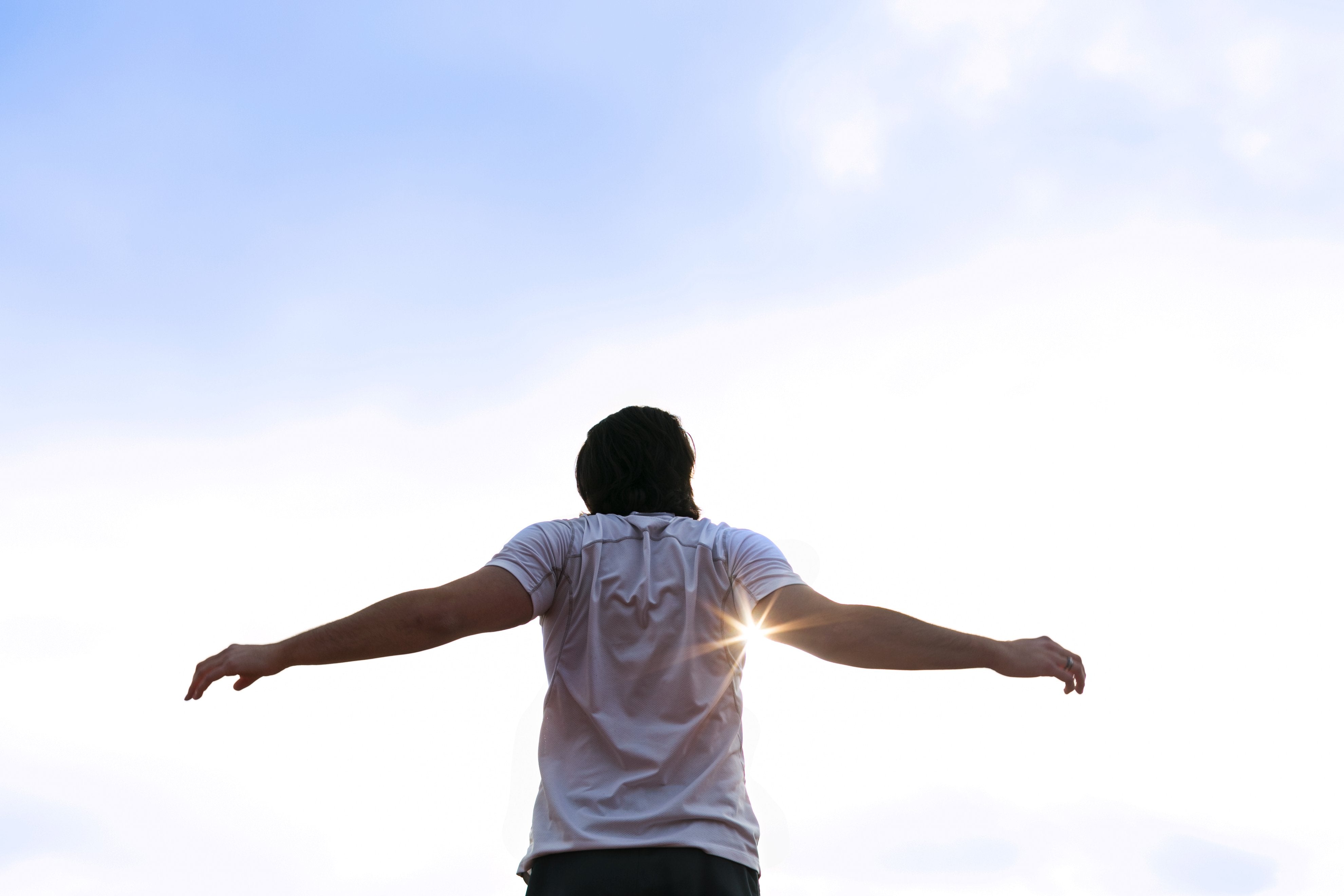 man stretching in the sun to release back tension