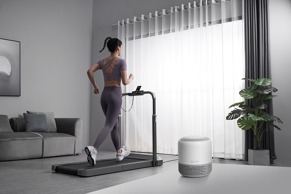 Woman using phone holder to play music while running on treadmill