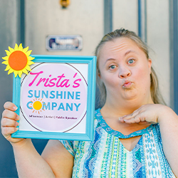 Image of Trista holding up a blue frame that say's Trista's
                Sunshine company