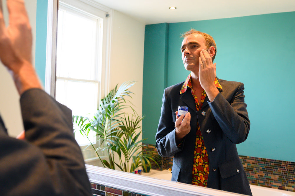 Man in bathroom mirror using face balm