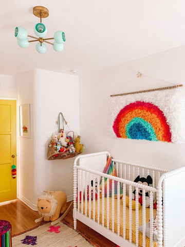 Buntes Kinderzimmer mit Regenbogenteppich und gelber Tür