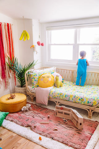 Buntes Kinderzimmer mit gemusterter Bettwäsche in Obstsalat und großem rosa Teppich
