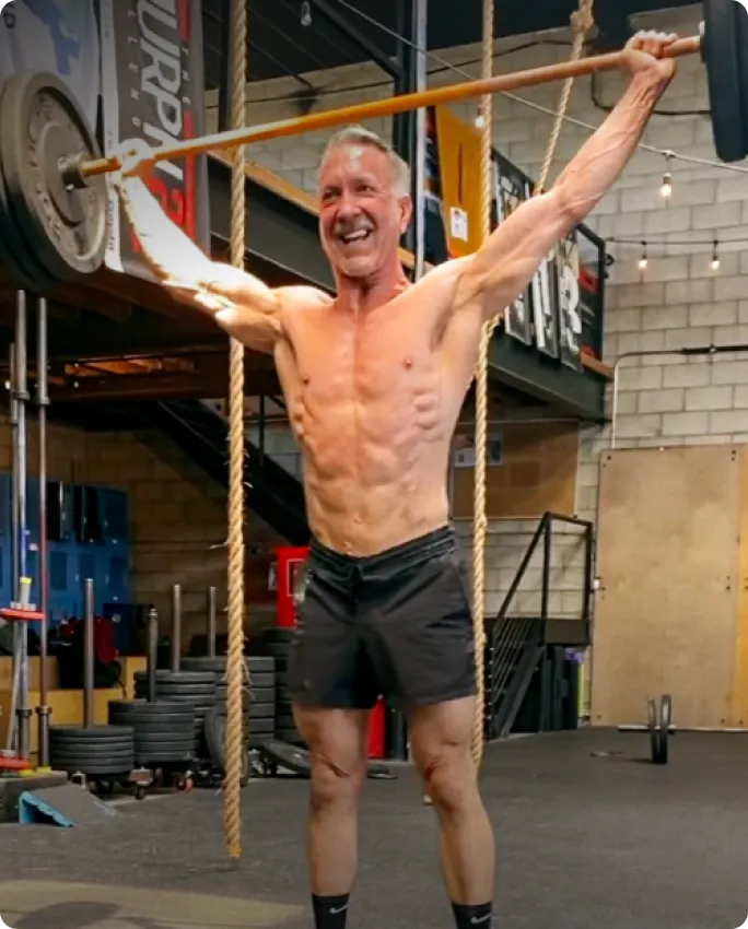 Man lifting a barbell overhead in a gym setting.