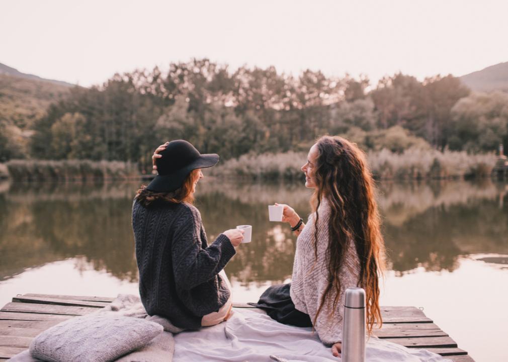 Two people drinking coffee outdoors. Drinking coffee outside. Drinking coffee in nature. Morning cup of coffee. Morning coffee.