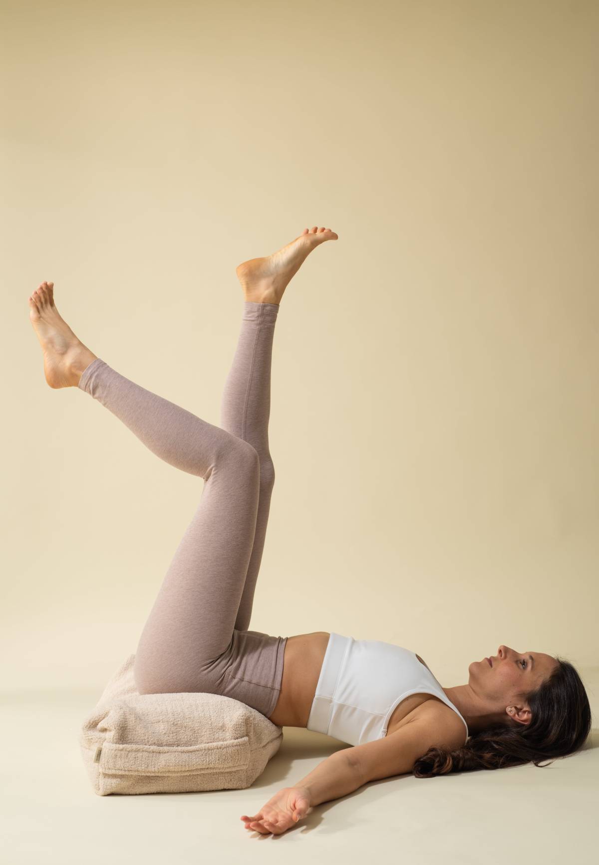 Women laying down on bolster pillow practicing yoga and meditation.