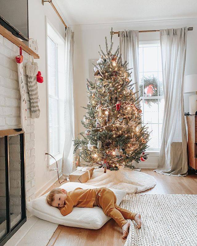 Little boy laying on floor next to Christmas tree. Living room Christmas tree. Christmas tree living room decor. Floor pillows. Living room large floor pillows.