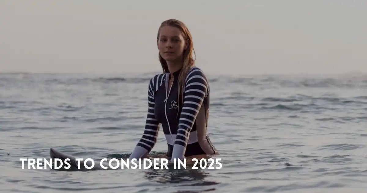 Woman in one-piece swimwear sits on a surfboard in the ocean.